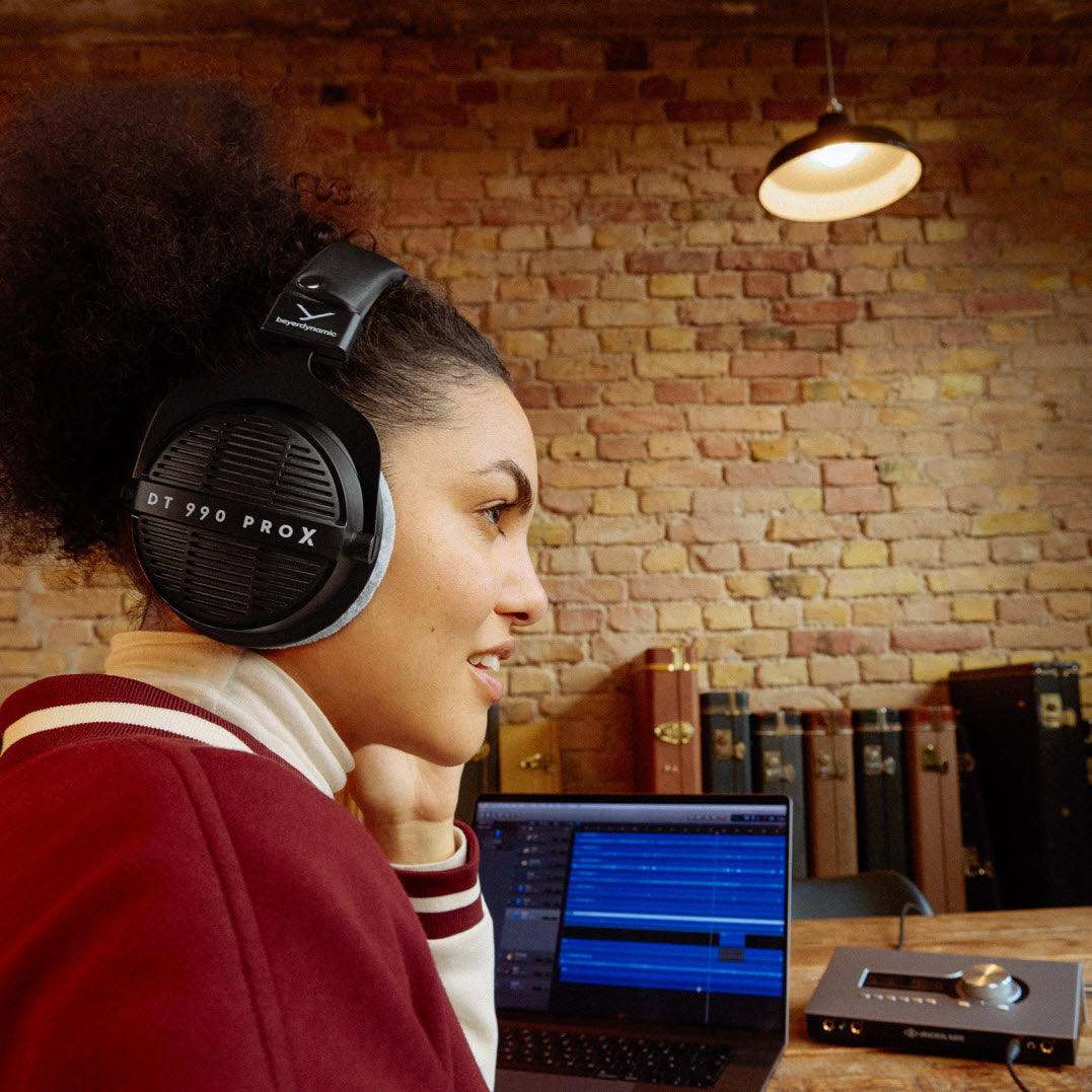 DT 990 PRO X headphones being used with a portable audio device and mac book